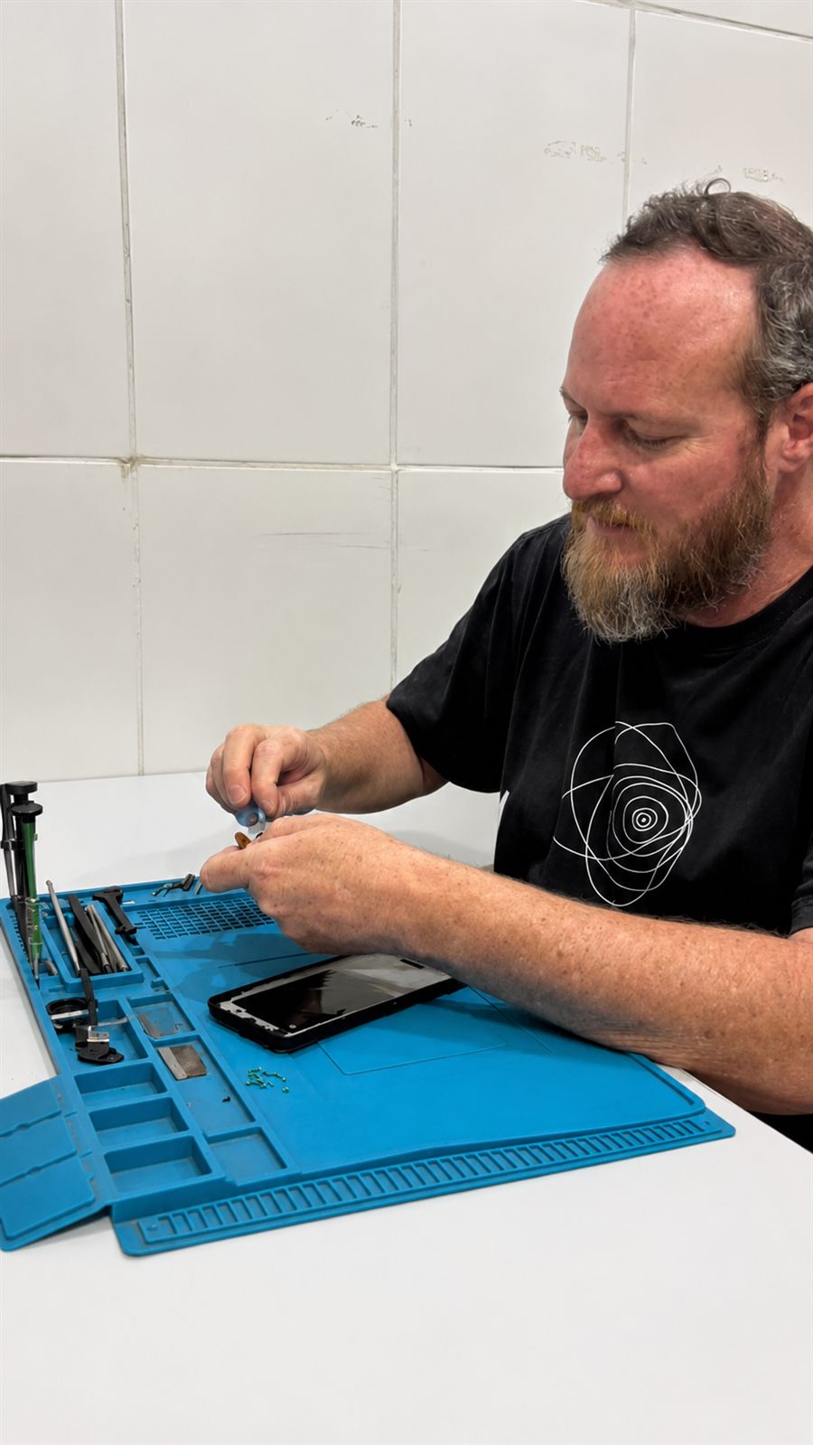 Técnico da Ev Start Tech reparando um celular na bancada