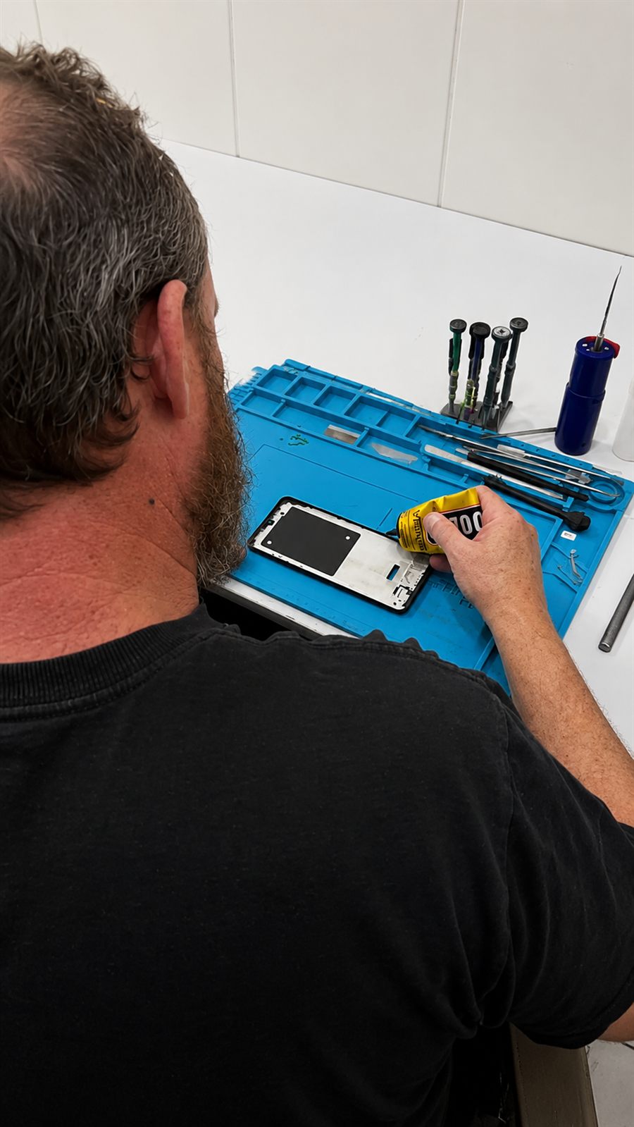 Técnico da Ev Start Tech aplicando cola de precisão durante o reparo de um aparelho